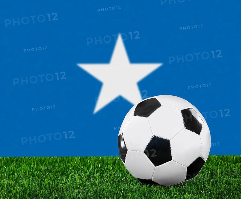 The Somalia flag and soccer ball on the green grass