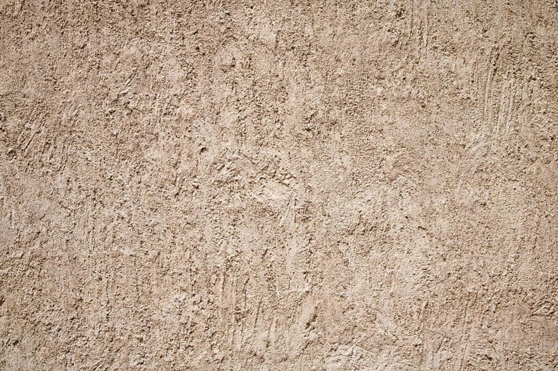 A close-up of a beige stucco wall with a rough textured surface