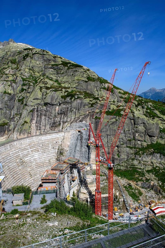 View of construction site of new dam for enlargement of reservoir Grimselsee replacement dam Spitallamm on the Grimsel in the Bernese Oberland, left old dam next to Grimsel Hospiz Grimselhospiz, right two large red cranes, Guttanen, Canton Bern, Switzerland, Europe