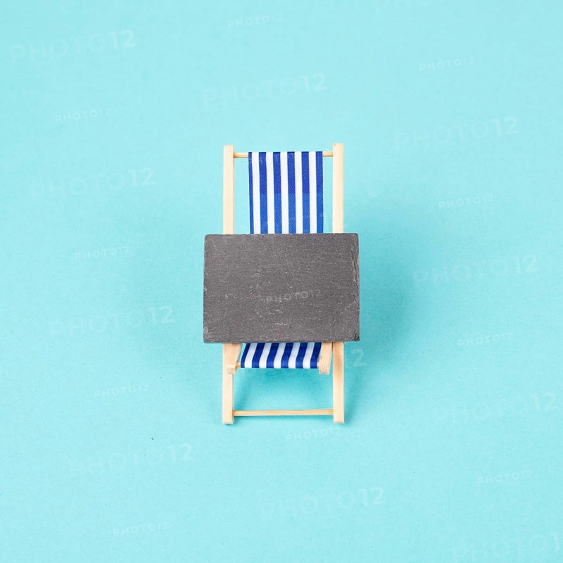 Lounge chair with a blank chalkboard sign, summer vacation travel by the sea
