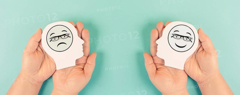 Holding a head with a sad and a happy face in the hands, mental health concept, positive and negative mindset, depression, support and evaluation symbol, emotion