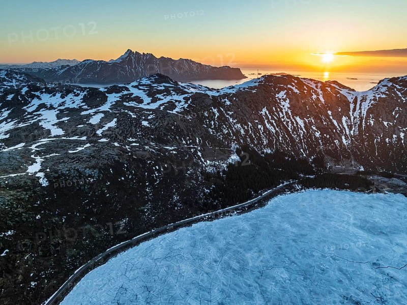 Aerial view of icy lake in front of steep mountains, coast, winter, sunrise, Storvatnet, Flakstadoya, Lofoten, Norway, Europe