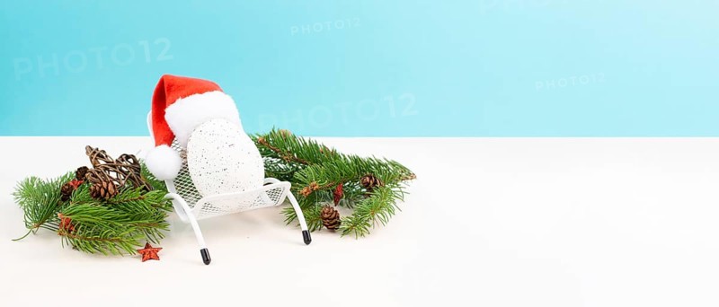 Santa Claus with a red hat sitting in a lounge chair, holiday by the sea, taking a vacation, christmas decoration with fir, cones and stars