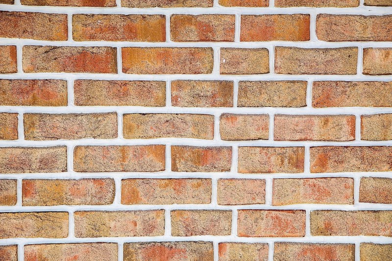 A close-up view of a rustic brick wall with red bricks and white mortar, background image
