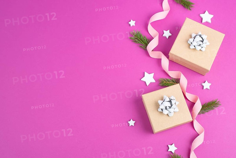 Christmas holiday background with little gift boxes, stars and fir branches, pink trendy background