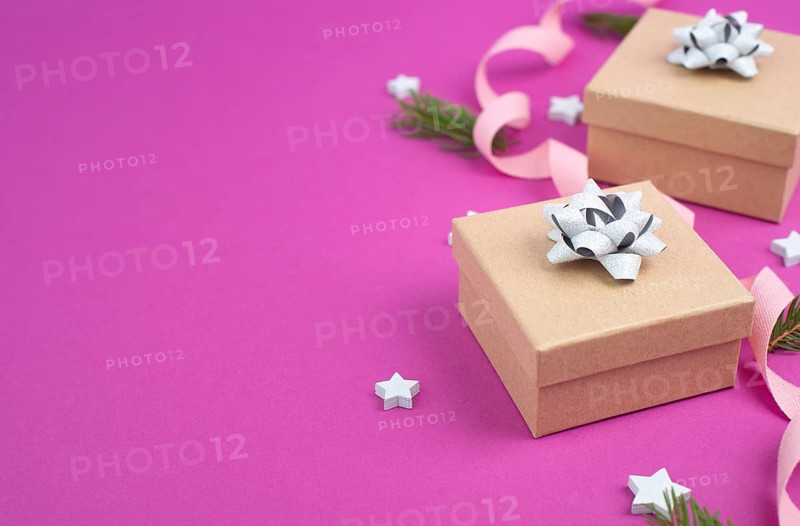 Christmas holiday background with little gift boxes, stars and fir branches, pink trendy background