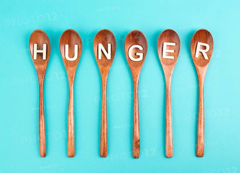 Hungry is standing in german language on the wooden spoons, food shortage and starving because of the war and inflation, political issue