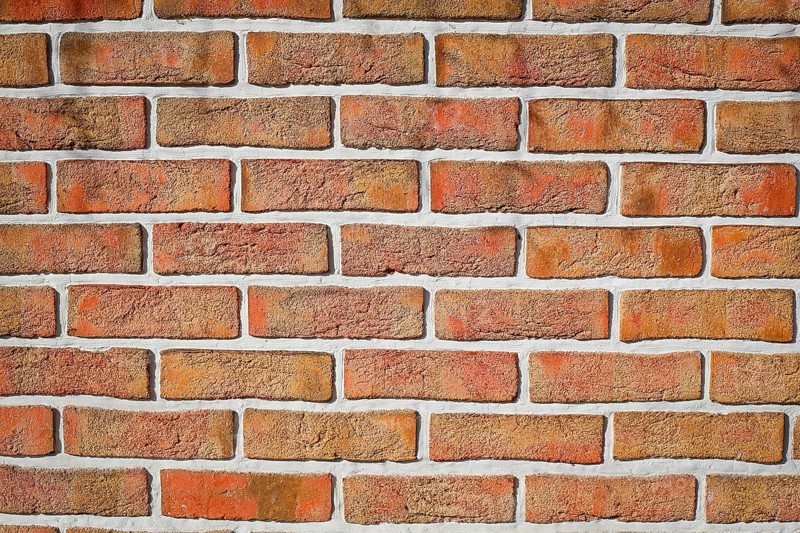 Weathered red brick wall with visible grout lines arranged in a horizontal pattern, background image