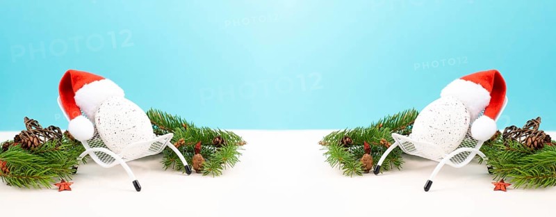 Santa Claus with a red hat sitting in a lounge chair, holiday by the sea, taking a vacation, christmas decoration with fir, cones and stars