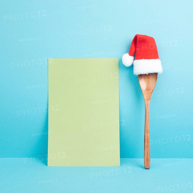 Blank paper with a wooden spoon and a red Santa Claus hat, christmas greeting card, copy space for a recipe for the holiday