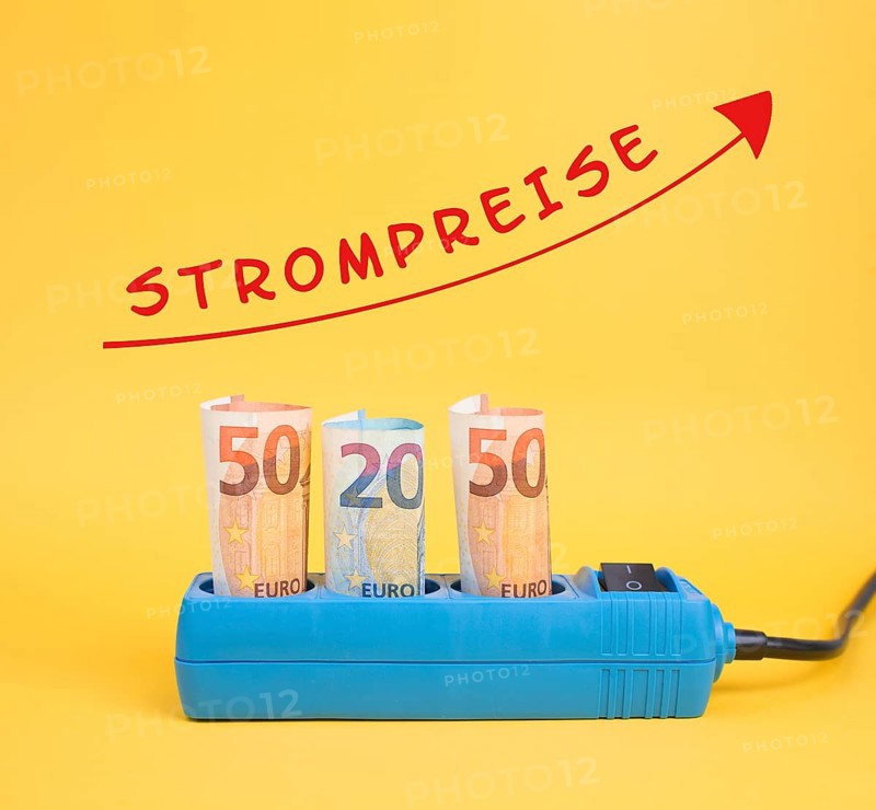 Euro banknotes in a power outlet, increasing prices for electricity is standing in german language over the arrow, expensive green energy, crisis in Ukraine and gas supply problems