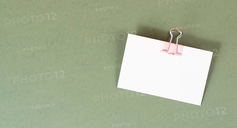 Blank white paper with a paperclip on a green colored background, copy space for text, reminder or message in the office, communication concept