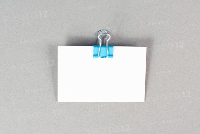Blank white paper with a paperclip on a graycolored background, copy space for text, reminder or message in the office, communication concept