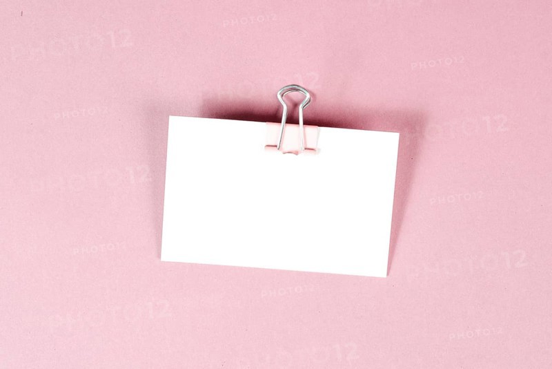 Blank white paper with a paperclip on a pink colored background, copy space for text, reminder or message in the office, communication concept