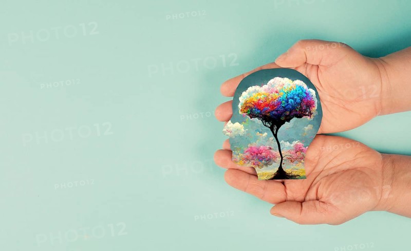 Holding a head with a colorful tree in the hands, symbol for creativity, connection to nature and positive emotion, living in a dream world