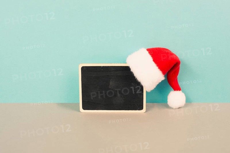 Red Santa Claus hat hanging on a chalkboard, greeting card for christmas, copy space for text, winter season