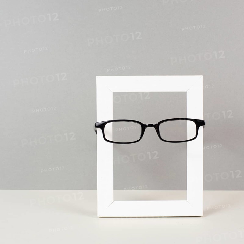 Home interior poster mock up with wooden frame and eyeglasses, gray wall background, copy space for text and pictures