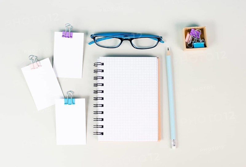 Blank notebook with a pen, paper and eyeglasses on a gray background, brainstorming for ideas, writing a message, workplace desk, home office