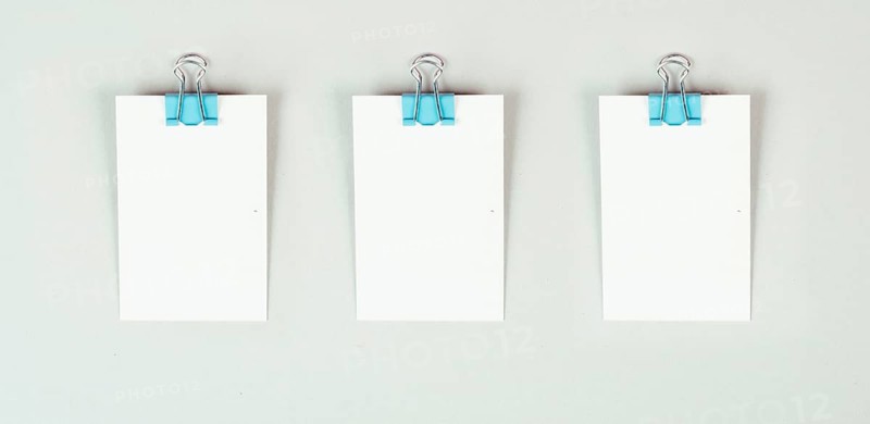 Blank white papers with a paperclip on a gray colored background, copy space for text, reminder or message in the office, communication concept
