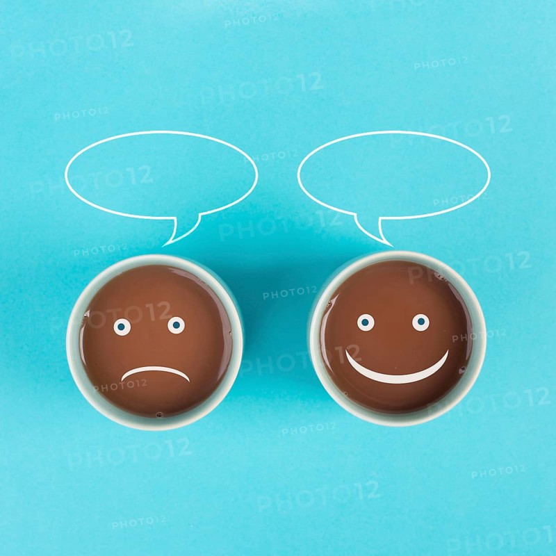Cup of coffee with a sad and a happy face, positive and negative mindset, support and evaluation concept, speech bubble