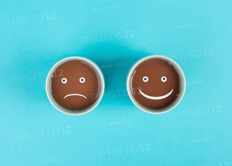 Cup of coffee with a sad and a happy face, positive and negative mindset, support and evaluation concept, emotion