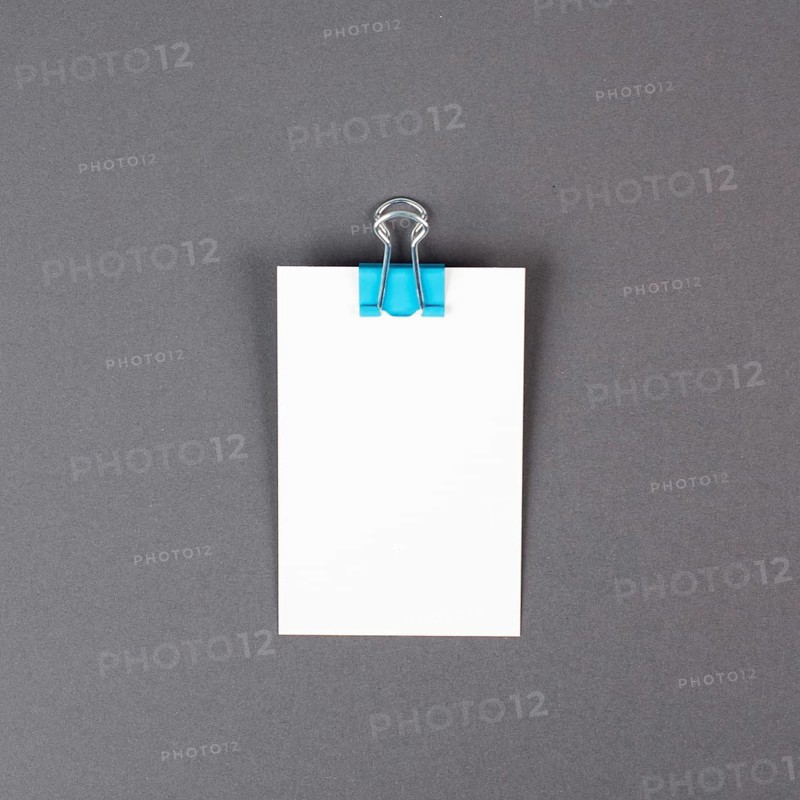 Blank white paper with a paperclip on a gray colored background, copy space for text, reminder or message in the office, communication concept