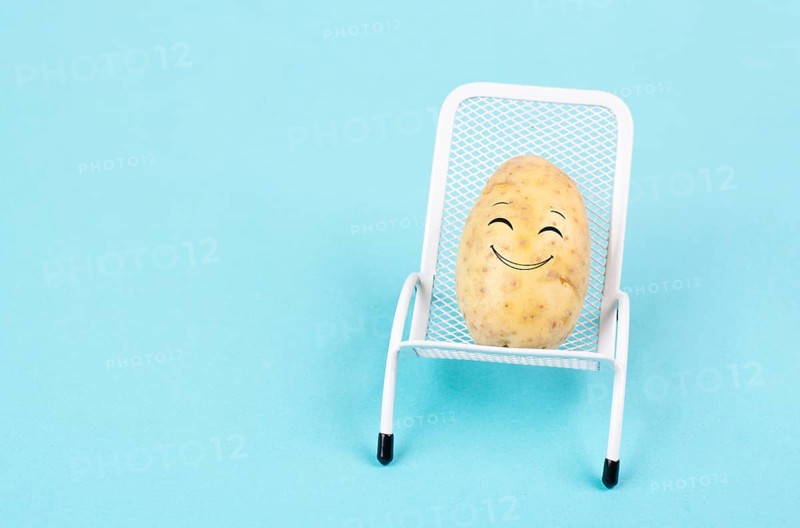 Potato with a funny face is sitting in lounge chairs, happy holiday, greeting card