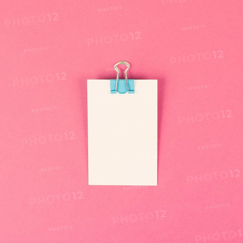 Blank white paper with a paperclip on a pink colored background, copy space for text, reminder or message in the office, communication concept