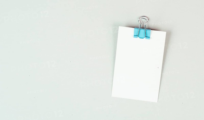 Blank white papers with a paperclip on a gray colored background, copy space for text, reminder or message in the office, communication concept