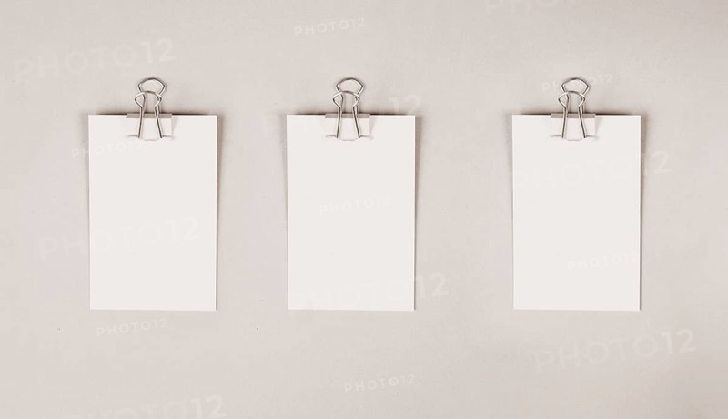 Blank white papers with a paperclip on a gray colored background, copy space for text, reminder or message in the office, communication concept