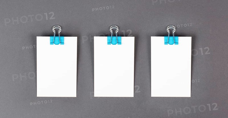 Blank white papers with a paperclip on a gray colored background, copy space for text, reminder or message in the office, communication concept