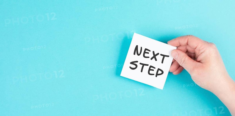 The phrase next step is standing on a paper, having new goals and strategies, making plans for future