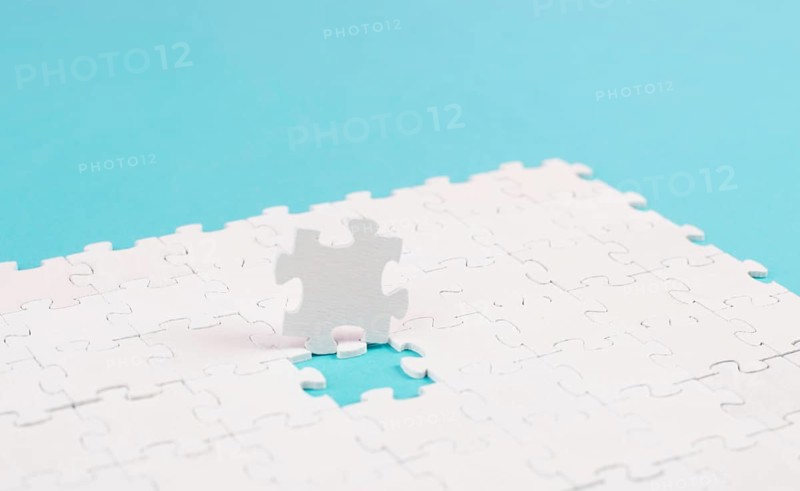 White jigsaw on a blue background, missing parts, working together as a team, searching for solutions, the last piece