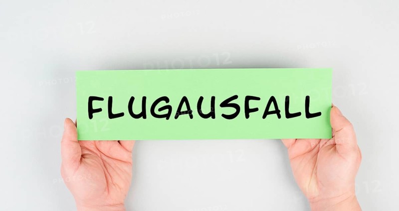 The word flight cancellation is standing in german language on the paper, staff shortage at the airport, vacation delayed