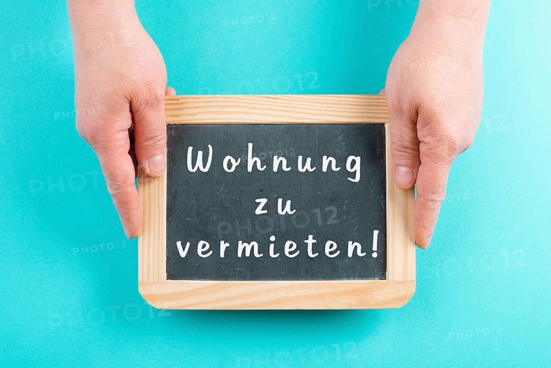 Holding a chalkboard in the hands, apartment for rent is standing in german language on the sign, moving to a new home, real estate