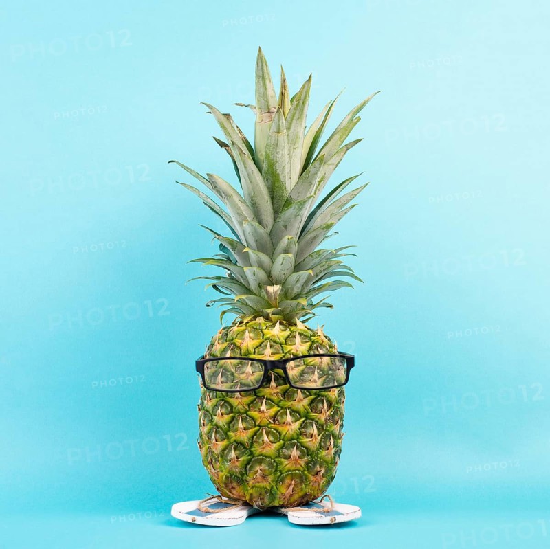 Pineapple with glasses and flip flops, vacation and travel concept, tropical summer holiday, funny fruit, blue background