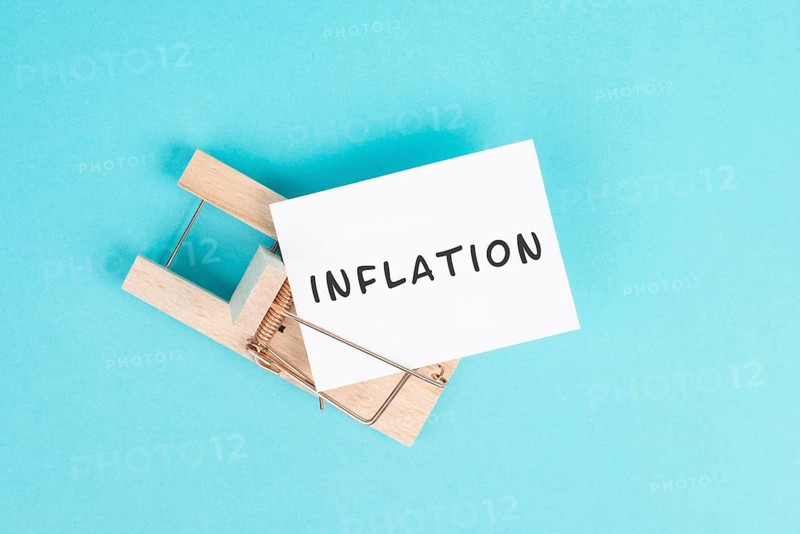 Paper with the word inflation in a mousetrap, high financial burden, increased costs and expenses for living, high prices caused by the crisis