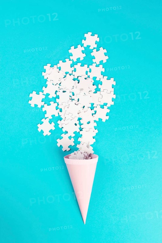 Cone with white puzzle pieces, blue background, spreading the jigsaw parts, searching for ideas and solutions, brainstorming as a team, flat lay