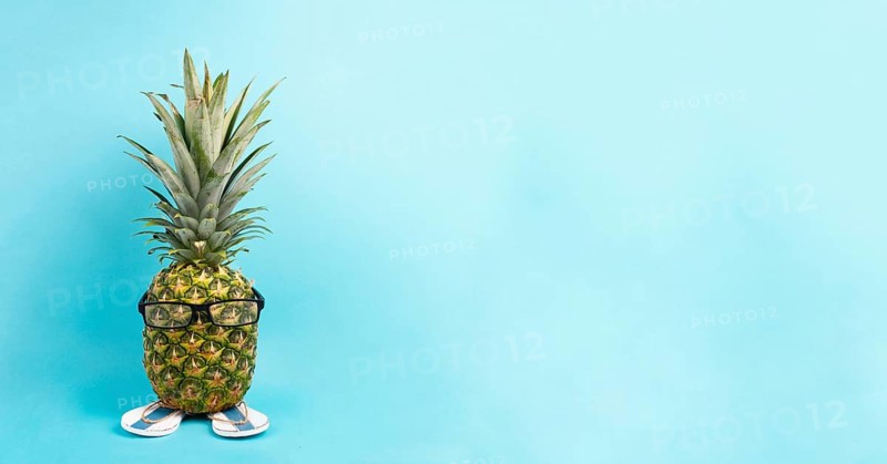 Pineapple with glasses and flip flops, vacation and travel concept, tropical summer holiday, funny fruit, blue background