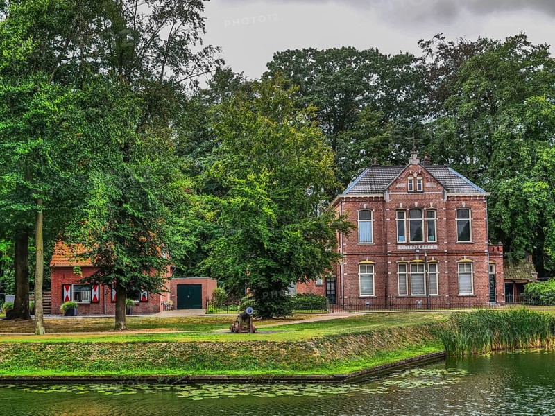 Large brick villa in a park with pond, surrounded by trees and green grass, groenlo, gelderland, the netherlands
