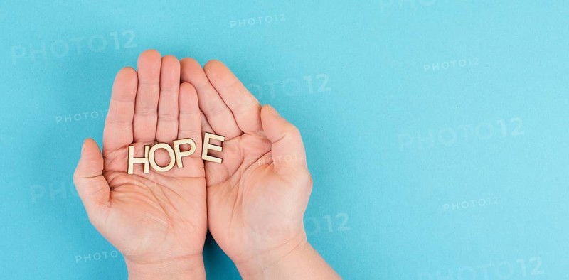 Holding the word hope in the palm of the hands, trust and believe concept, having faith in the future, hopeful positive mindset