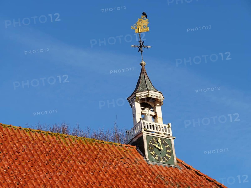 Church tower with clock and golden weather vane under a clear sky, greetsiel, east frisia, germany