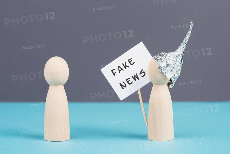 Alu hats protester talking to a person, conspiracy theories, tin foil on the head, holding a sign with fake news, conversation and communication concept