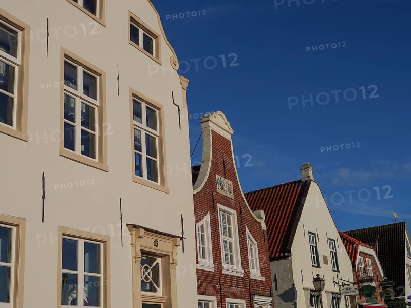 Close-up of various house facades with white and brick fronts under a cloudless sky, greetsiel, east frisia, germany