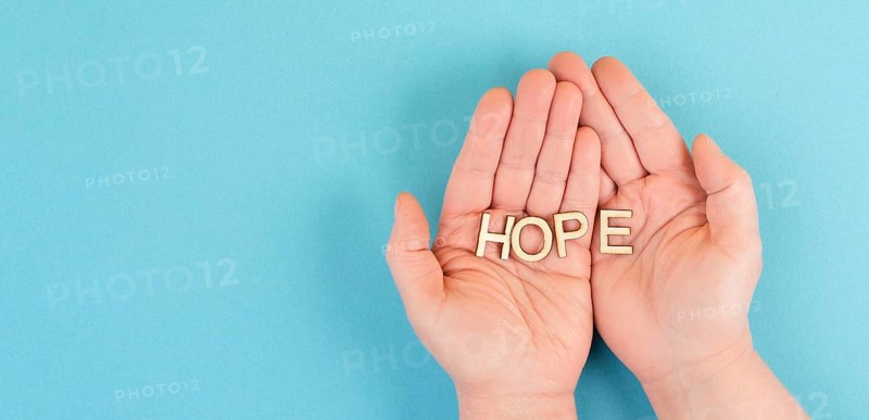 Holding the word hope in the palm of the hands, trust and believe concept, having faith in the future, hopeful positive mindset