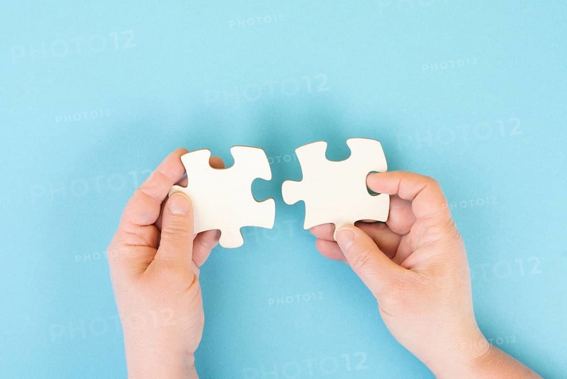Holding two pieces of a puzzle in the hands, connecting together as a team, solving a problem, strategy and communication concept