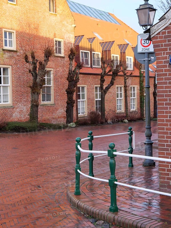 A quiet street with brick houses and bare trees under a lantern in a traffic-calmed zone, greetsiel, east frisia, germany