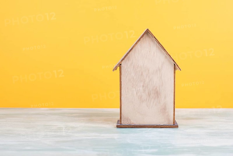 Wooden house, yellow background, buying or renting a house, real estate concept, booking home for vacation, copy space for text
