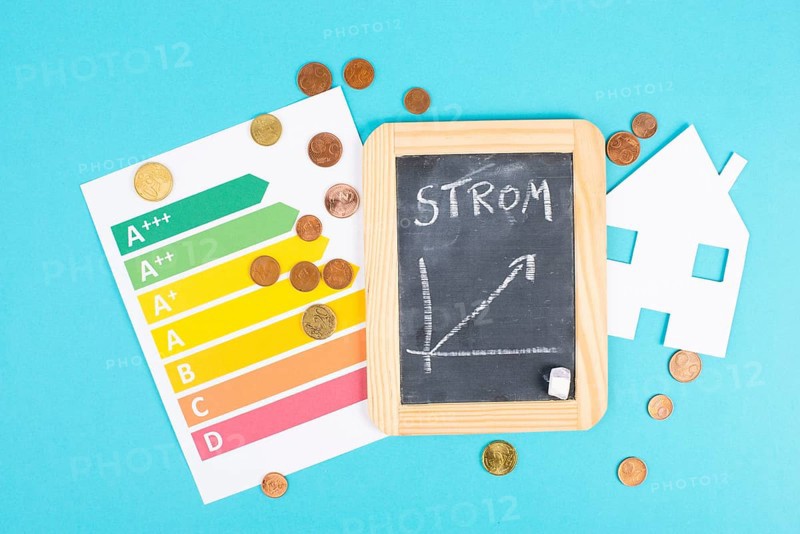 Chalkboard with the german word for electricity, Euro money coins, power consumption grafic, increasing energy costs, green technology, inflation, poverty and environmetal issue