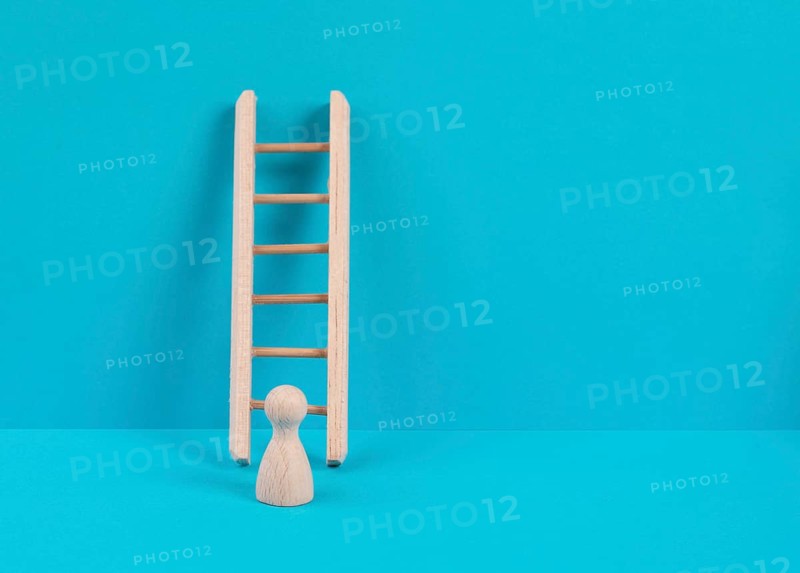 Man is standing next to a ladder, climbing up in career, having a goal, brainstorming for ideas, success strategy, taking a challenge, business concept